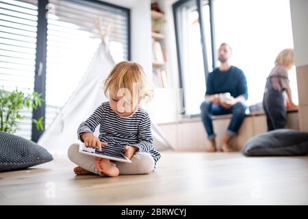 Nettes kleines Kleinkind Mädchen drinnen im Schlafzimmer spielen mit Tablet. Stockfoto