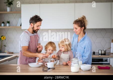 Junge Familie mit zwei kleinen Kindern im Haus in der Küche, Kochen. Stockfoto