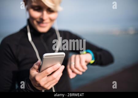 Eine junge Sportlerin mit Smartphone im Freien am Strand. Stockfoto