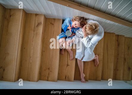 Draufsicht des kleinen Mädchens mit Mutter drinnen zu Hause, auf der Treppe am Morgen sitzen. Stockfoto