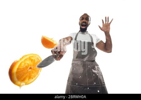 Erstaunlich afroamerikanischen Mann, der unglaubliche Essen mit Aktion, Details und helle Emotionen, professionelle Koch isoliert auf weißem Studio Hintergrund. Moderne Küche, Kunstwerke. Nahaufnahme, Weitwinkel. Stockfoto