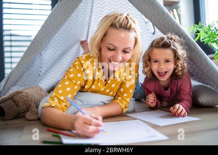 Ein nettes kleines Mädchen mit Mutter drinnen zu Hause, Bilder zeichnen. Stockfoto