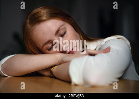 Müde junge Geschäftsfrau sitzt am Schreibtisch drinnen im Büro, schläft. Stockfoto