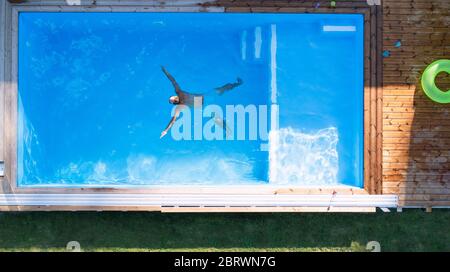 Von oben gesehen, wie der Mann im Wasser im Swimmingpool im Freien schwimmte. Stockfoto