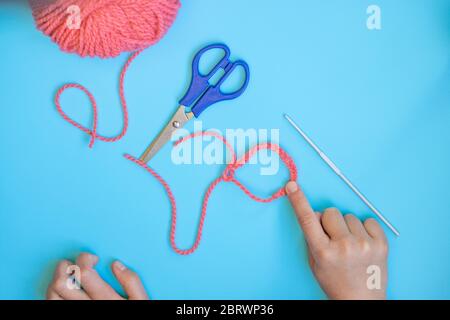 Schritt-für-Schritt-Anleitung für Kinder, wie man ein Armband aus dem Garn häkelt Stockfoto