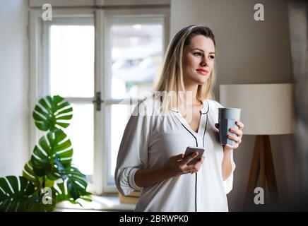 Junge Frau mit Smartphone im Home Office. Stockfoto