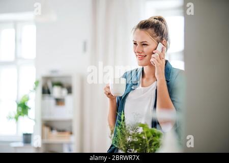 Junge Frau mit smartpone im Haus, genießen Sie eine Tasse Kaffee. Stockfoto