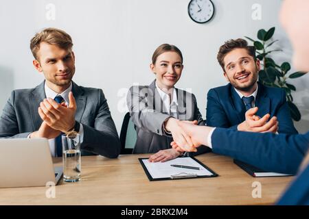 Selektiver Fokus: Lächelnder Personalvermittler, der im Büro die Hand zum Mitarbeiter schüttelt Stockfoto