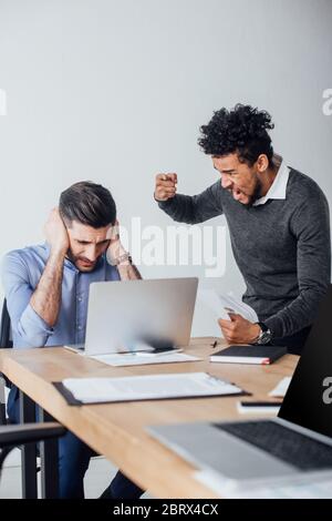 Selektiver Fokus des wütenden afroamerikanischen Geschäftsmann Streit an Kollegen Ohren im Büro Stockfoto