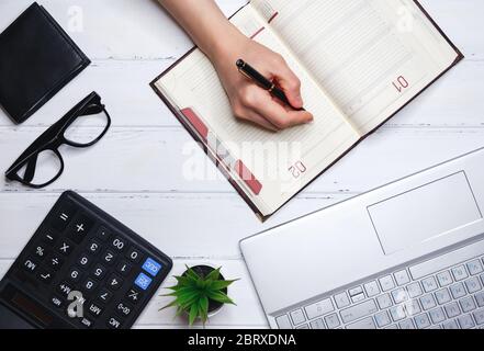 Die menschliche Hand schreibt Pläne für Aktuelles, Training, Umsetzung und Geschäftsentwicklung in das tägliche Tagebuch.Konzept von Planung und Erfolg Stockfoto