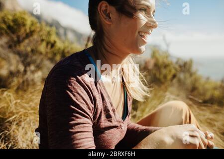 Eine Wanderin sitzt auf einem Felsen und schaut weg auf die Aussicht. Bergsteigerin beim Blick auf die Bergspitze. Stockfoto