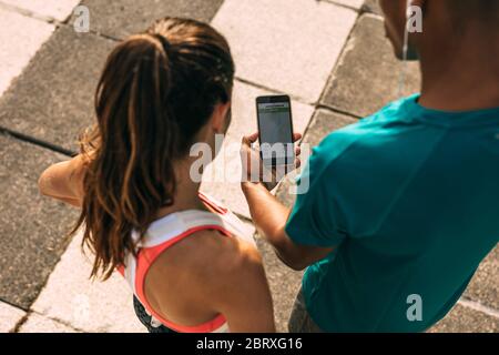 Läuferin und Läuferin mit einer Fitness-App auf dem Mobiltelefon. Fitness-Teilnehmer überprüfen die Zusammenfassung ihres Laufs auf dem Smartphone. Stockfoto