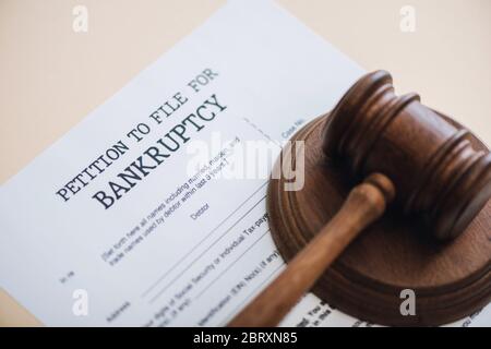 Hohe Winkelansicht von Gavel auf Dokument mit Petition für Insolvenz-Beschriftung auf beige isoliert Datei Stockfoto