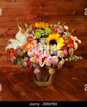 Blumenstrauß mit Lilie, Sonnenblume, Chrysantheme, Eukalyptus, Strauchrose auf Holzbrett Stockfoto