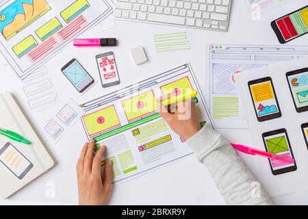 Ein Website-Designer arbeitet an einer Anwendungsschnittstelle. Der Entwickler zeichnet Skizzen von Benutzeranwendungen für Smartphones. Stockfoto