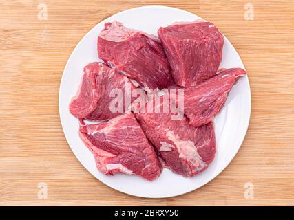 Rohe große Stücke Rindfleisch für bbq oder Gulasch Fleisch auf weißem Teller, Draufsicht Stockfoto