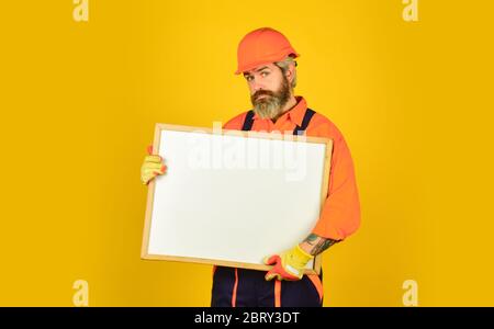 Mann in harter Mütze. Builder zeigt auf Flipchart. Architekt Arbeiter halten Flipchart. Präsentieren Flipchart bei der Sitzung. Männliche Bauarbeiter. Copy Raum. Planung neuer Projekt. Serious Mann Präsentation. Stockfoto
