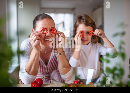 Kleines Mädchen mit älterer Großmutter in der Küche drinnen zu Hause, Spaß haben. Stockfoto