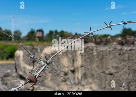 Nahaufnahme von Stacheldraht mit einem verschwommenen Wachturm im Hintergrund Stockfoto