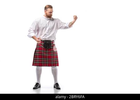Ernster schottischer Rotschopf-Mann in rotem Kilt auf weißem Hintergrund Stockfoto
