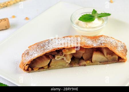 Traditionelles Stück Apfelstrudel mit Puderzucker und Minze Closeup auf einem Tisch. horizontale Stockfoto