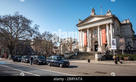 Das Tate Britain Museum und die Galerie in Millbank, Westminster, mit traditionellen schwarzen Taxis, die auf einen Fahrpreis warten. Stockfoto