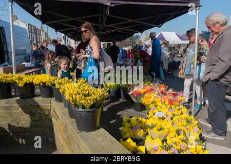 Leute kaufen Narzissen und Ranunkeln am Blumenstand auf dem wöchentlichen Samstagmarkt auf dem Parkplatz der Union Road, High Street in Deal, Kent Stockfoto