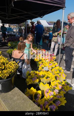 Leute kaufen Narzissen und Ranunkeln am Blumenstand auf dem wöchentlichen Samstagmarkt auf dem Parkplatz der Union Road, High Street in Deal, Kent Stockfoto