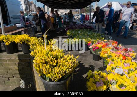 Leute kaufen Narzissen und Ranunkeln am Blumenstand auf dem wöchentlichen Samstagmarkt auf dem Parkplatz der Union Road, High Street in Deal, Kent Stockfoto