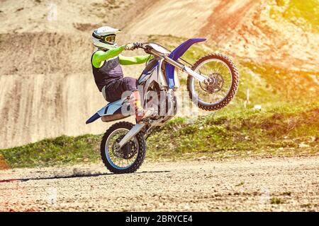 Motocross, steht ein Fahrer auf dem Hinterrad eines Fahrrads, Reiten auf dem Hinterrad. Extreme, Industrie, Motorrad-Cross-Country-Reiten für extreme. Stockfoto