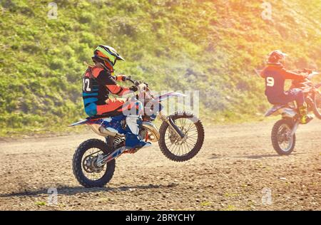 Ein Team von Mountainbike-Athleten startet, Rauch und Staub fliegen unter den Rädern Off-Road. Motocross Outdoor-Aktivitätskonzept. Stockfoto