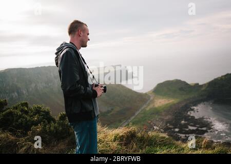 Junger Tourist mit Blick auf den Giants Causeway, UNESCO-Weltkulturerbe in Nordirland, der jetzt vom National Trust verwaltet wird. Stockfoto