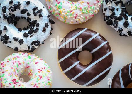 Flach legen Bild von Donut mit Schokolade Glasur mit Streifen amids anderen verschiedenen Donuts Stockfoto