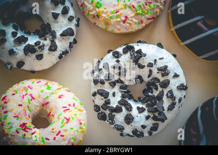 Flach legen Bild von Donut mit weißer Glasur und schwarzen Cookies amids anderen verschiedenen Donuts Stockfoto