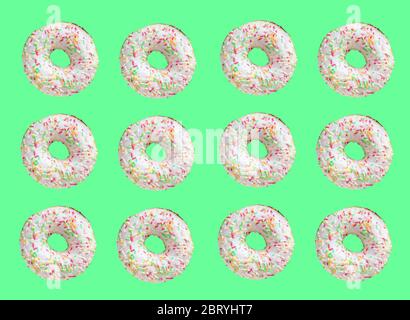 Muster aus Ring Donuts mit weißer Glasur und einfallsreichen Hunderttausenden auf grünem Hintergrund Stockfoto