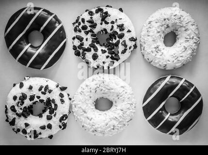 Flach legen Bild von sechs Ring Donuts mit weißer Glasur und Hunderte und Tausende, Schokolade und Streifen und weiße Glasur mit schwarzen Cookies Stockfoto