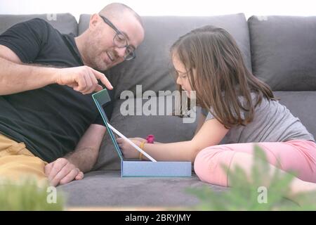 Vater und Tochter zu Hause spielen auf dem Sofa. Selbstisolierung mit Familie und Kindern Konzept mit leerem Kopierplatz für Editor-Inhalte. Stockfoto