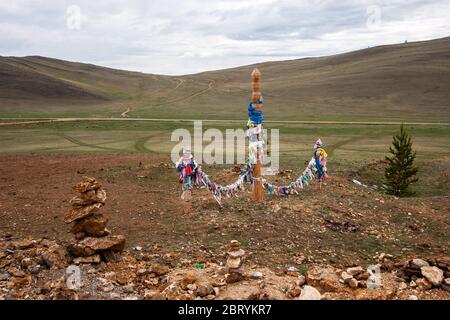 Die heiligen Säulen mit den Bändern für schamanistischeRiten auf dem Hintergrund der Hügel. Schamanistische Ritus von Burjatien. Cairn in der Nähe. Horizontal. Stockfoto