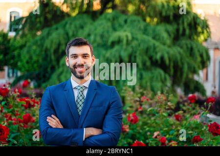 Junger attraktiver Geschäftsmann mit blauem Anzug und Krawatte im Outdoor Park Stockfoto