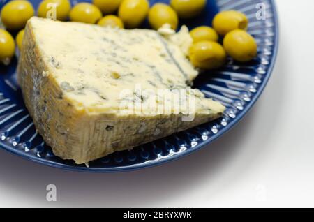 Voll Fett weichen blauen Adernkäse und eingelegte Oliven gefüllt Knoblauch auf dem blauen Teller, leckere Vorspeise Stockfoto