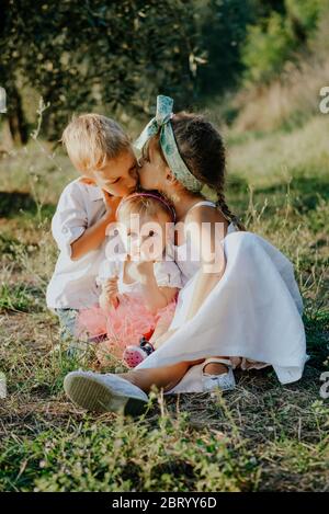 Porträt von zwei Mädchen und einem Jungen in einem sonnigen Garten sitzen. Stockfoto