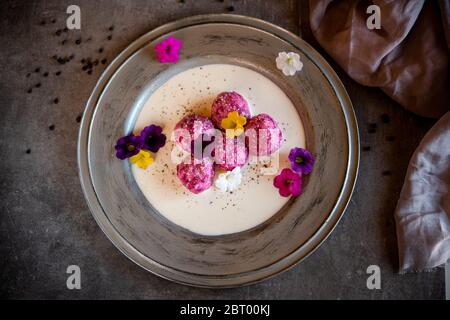 Hohe Winkelnahaufnahme von Knödeln mit Baby rosa Rüben und blauem Käse auf weißem Teller mit grauem Rand. Stockfoto