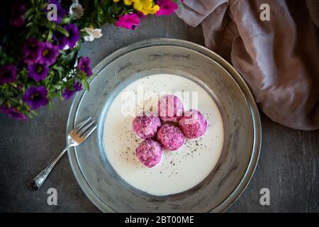 Hohe Winkelnahaufnahme von Knödeln mit Baby rosa Rüben und blauem Käse auf weißem Teller mit grauem Rand. Stockfoto