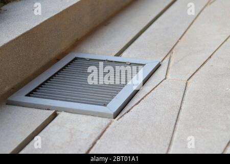 Graue Ablaufabdeckung auf dem Boden. Grauer Schachtdeckel aus Eisen mit Gitterrost. Stockfoto