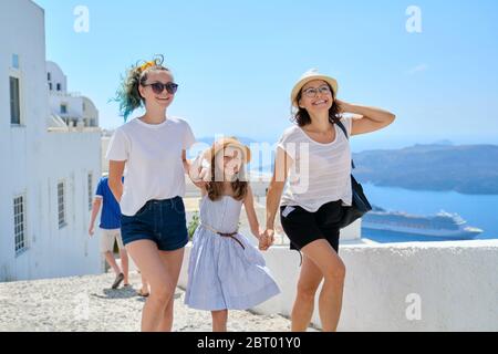Mutter geht mit zwei Töchtern, die Hand in Santorini halten Stockfoto