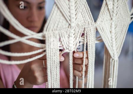 Nahaufnahme von Frau, die auf cremefarbenen macrame Vorhang. Stockfoto