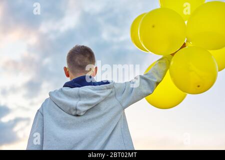 Teen junge mit Luftballons laufen, Blick zurück Stockfoto