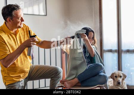 Vater schneidet seiner Tochter die Haare zu Hause, während der Lockdown Stockfoto