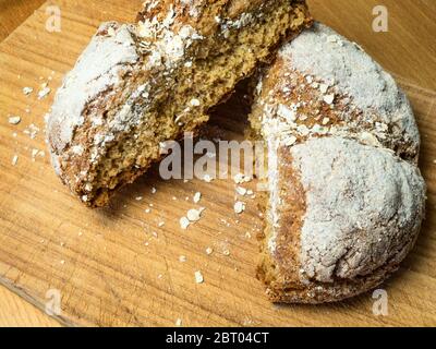 Frisch gebackener Soda-Brot-Laib in zwei Hälften auf einem hölzernen Brottafel zerrissen Stockfoto