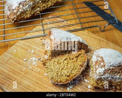 Frisch gebackenes Sodabrot, das auf einem hölzernen Brotscheiben mit einem halben Laib auf einem Drahtscheiben geschnitten wurde Stockfoto